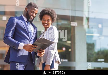 Couple of african american business partners working while standing outdoors Stock Photo