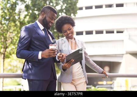 Two smiling coworkers discussing new project while standing outdoors Stock Photo