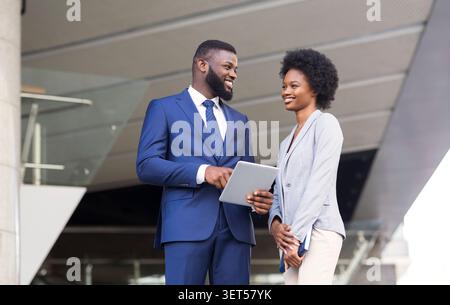 Happy young fellow workers browsing internet on digital tablet outdoors Stock Photo