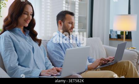 Happy gadget addicted family Caucasian working with laptops using two computer busy with online work smiling cheerful man chatting in internet smile Stock Photo