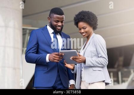 Business people using digital tablet and discussing new project outdoors Stock Photo