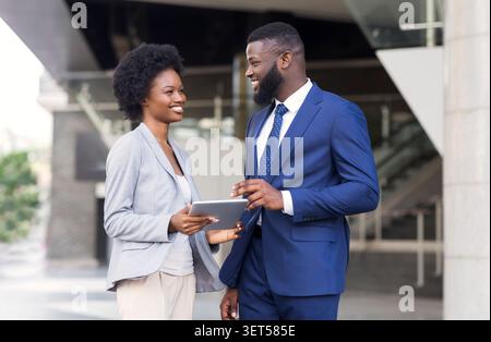 Happy young fellow workers browsing internet on digital tablet outdoors Stock Photo