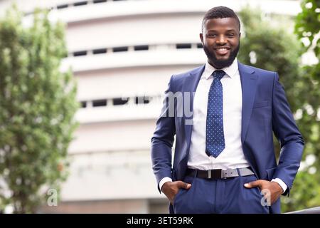 Handsome black man in suit against modern office center background Stock Photo