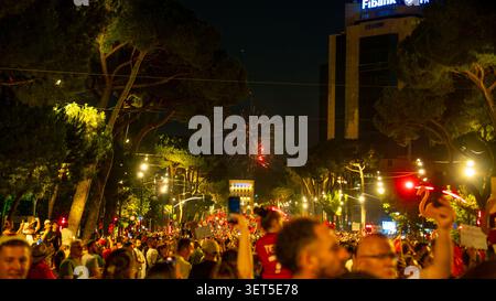Tirana, Albania – 20 June 2026: Fireworks appear above a crowd of protesters gathered along a brightly lit boulevard at night. Stock Photo
