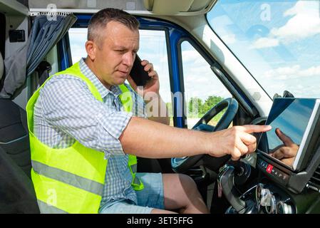 Delivery man in safety vest touching digital dashboard monitor in commercial vehicle Stock Photo