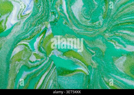 Abstract green and blue paint swirling, creating a marbling texture and pattern Stock Photo