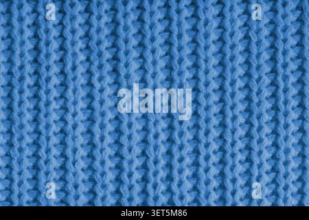 Close up, macro of blue knitted fabric texture with visible yarn stitches and soft wool pattern. Cozy textile backdrop, cloth background, fashion wall Stock Photo