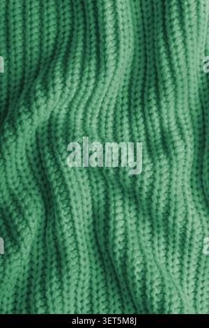 Close up, macro of crumpled green colored knitted fabric. Cloth with visible wrinkles, folds and soft waves. Soft wool material texture with detailed Stock Photo