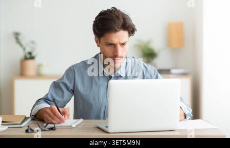 Focused Man Working on a Laptop in a Bright and Modern Office Environment Stock Photo