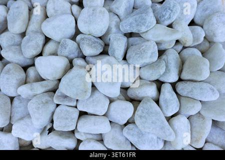 White polished pebbles creating a natural background, showing different shapes and sizes of smooth quartz stones used for garden landscaping and zen d Stock Photo