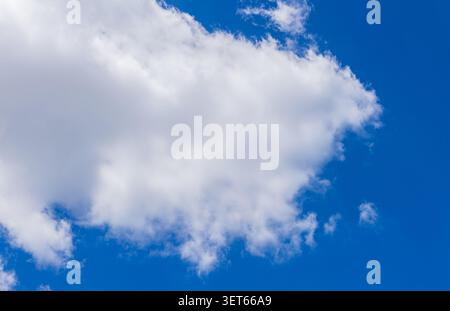 Large white cloud floating in a deep blue summer sky Stock Photo