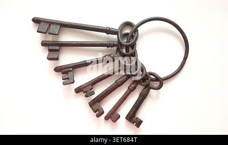 Collection of old metal keys on a ring lying on a flat surface in a bright setting during daylight Stock Photo