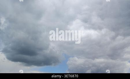 Cloudy sky with shades of grey and blue at a high altitude in the afternoon revealing hints of sunlight breaking through the clouds Stock Photo
