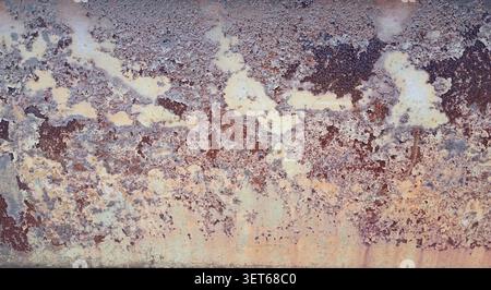 Close view of rusty metal surface with peeling paint and corrosion patterns showing orange and brown colors in natural light on a sunny day Stock Photo