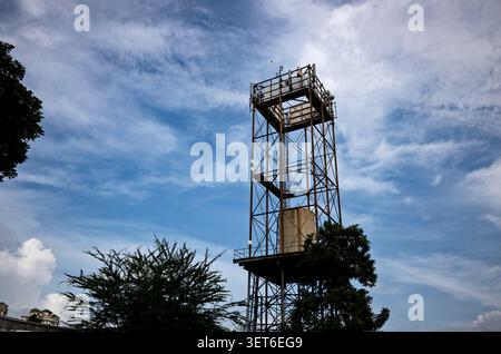 Industrial Telecommunications Tower and Water Tank Against Dynamic Sky Stock Photo