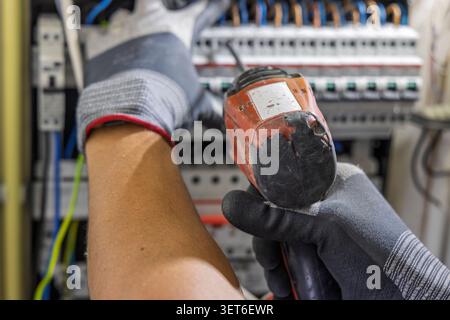 Utrecht, Netherlands - June 01, 2026: An over-the-shoulder perspective of a technician using a cordless drill to secure components in a modern residen Stock Photo