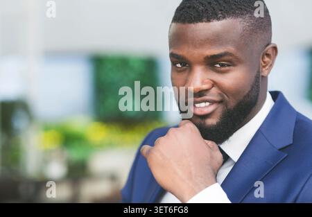 Thoughtful Afro Businessman Touching Chin Looking At Camera In Cafe Stock Photo