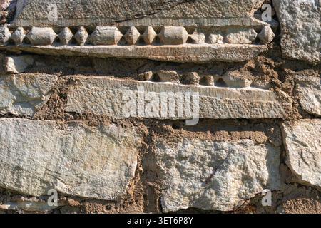 Close-up of carved stone blocks with ornamental relief patterns in ancient masonry, showing architectural heritage and weathered archaeological detail Stock Photo