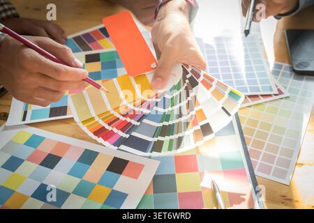 Interior designer chooses a color chart for home design. Graphic designers working on color chart at modern office. Stock Photo