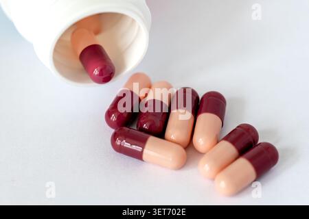 A close up of loose medicine capsules and opened pill bottle isolated on white. Stock Photo