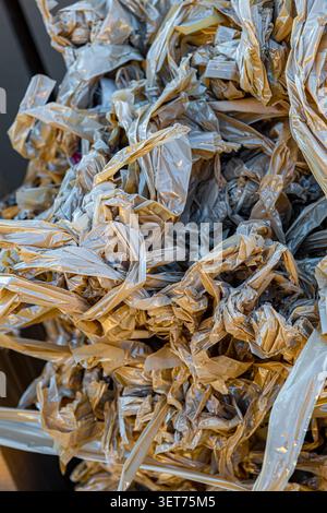 A detailed texture of crumpled plastic packaging film intertwined with strips of adhesive torn tape Stock Photo