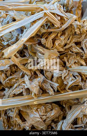 A detailed texture of crumpled plastic packaging film intertwined with strips of adhesive torn tape Stock Photo