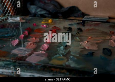 A glass oil painters palette with mixed colours organized by shade in pinks, greens and soft oranges. Stock Photo
