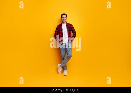 Smiling Young Caucasian Man Posing With Hands In Pockets On Yellow Background Stock Photo