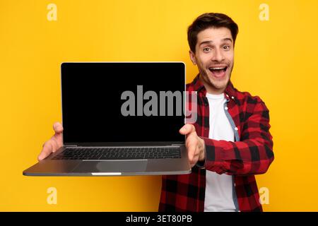 Happy Male Holding Laptop With Blank Screen, Smiling In Studio, Technology Concept Stock Photo