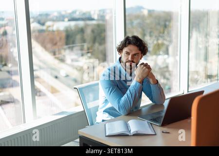 Serious Young Man Working At Office Desk, Focused And Contemplative, Business Concept Stock Photo