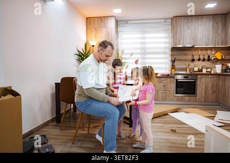 Family bonding time as father and daughters assemble a new project Stock Photo