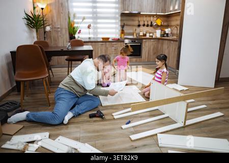 Family bonding moments during home assembly project in cozy kitchen Stock Photo