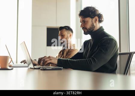 Focused Caucasian Male And Male Working Together In Modern Office, Business Concept Stock Photo