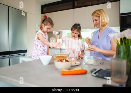 Mom and daughters creating tasty treats in the kitchen Stock Photo