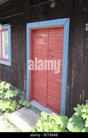 Old red wooden door in Visby, Gotland, Sweden, set in a historic medieval stone building. Stock Photo
