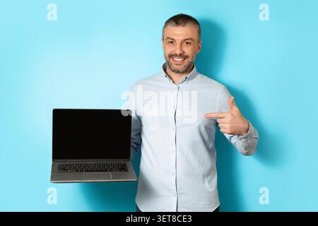 Smiling Caucasian Man Holding Laptop And Pointing At Screen, Studio, Business Concept Stock Photo