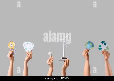 Female hands with wind turbine model, light bulbs and recycle signs on light background. Ecology concept Stock Photo