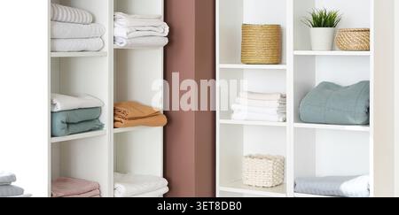 Organized home linen closet with folded towels, blankets, and decorative baskets for storage and interior design Stock Photo