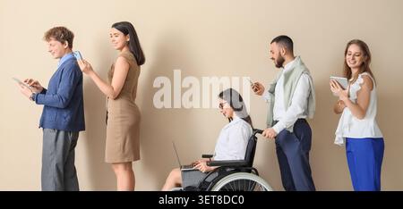 Diverse group of people in line using digital devices, including woman in wheelchair with laptop, modern technology and accessibility Stock Photo