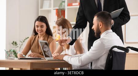 Diverse business team collaboration in modern office, inclusive workplace with disabled employee and manager Stock Photo