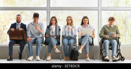 Diverse group of job candidates waiting for interview, business professionals and young adults in a modern office setting Stock Photo