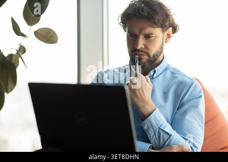Focused Caucasian Male Working On Laptop In Modern Office, Business Concept Stock Photo