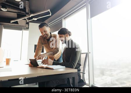 Two Smiling Men Collaborating And Using Tablet In Office, Teamwork Concept Stock Photo