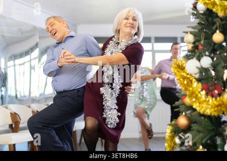Happy caucasian adult man and lady dancing rock and roll dance in dance studio during celebration Christmas and New Year Stock Photo