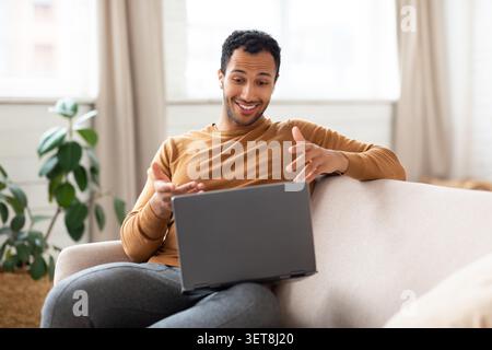 Smiling Young Black Man Using Laptop, Communicating At Home, Relaxed Lifestyle Concept Stock Photo
