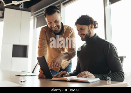 Happy Caucasian Men Collaborating On Digital Tablet In Modern Office, Business Concept Stock Photo