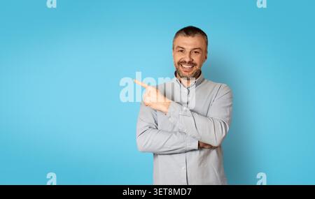 Smiling Caucasian Man Pointing To Blank Space On Blue Background, Business Concept Stock Photo
