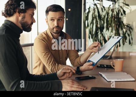Focused Male And Female Business Professionals Discussing Project Details At Office Table Stock Photo