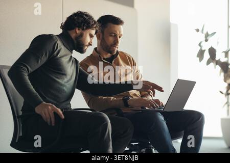 Two Men Collaborating At Desk In Modern Office, Business Concept Stock Photo