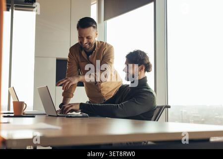 Two Men Collaborating On Laptop In Modern Office, Business Concept Stock Photo